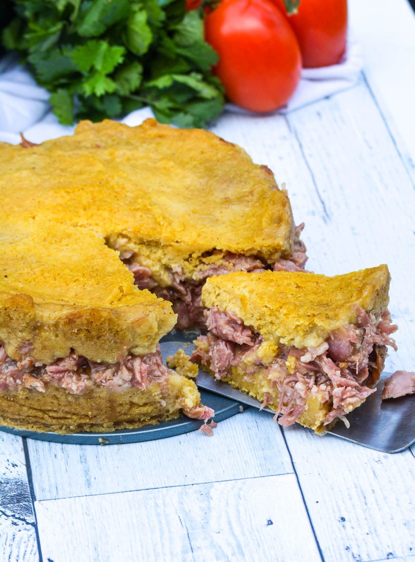a spatula removing a single slice of tamale pork pie from the whole pie