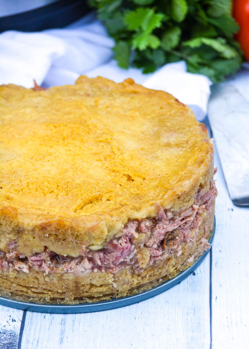 pulled pork stuffed tamale pie on a springform pan on a wooden table