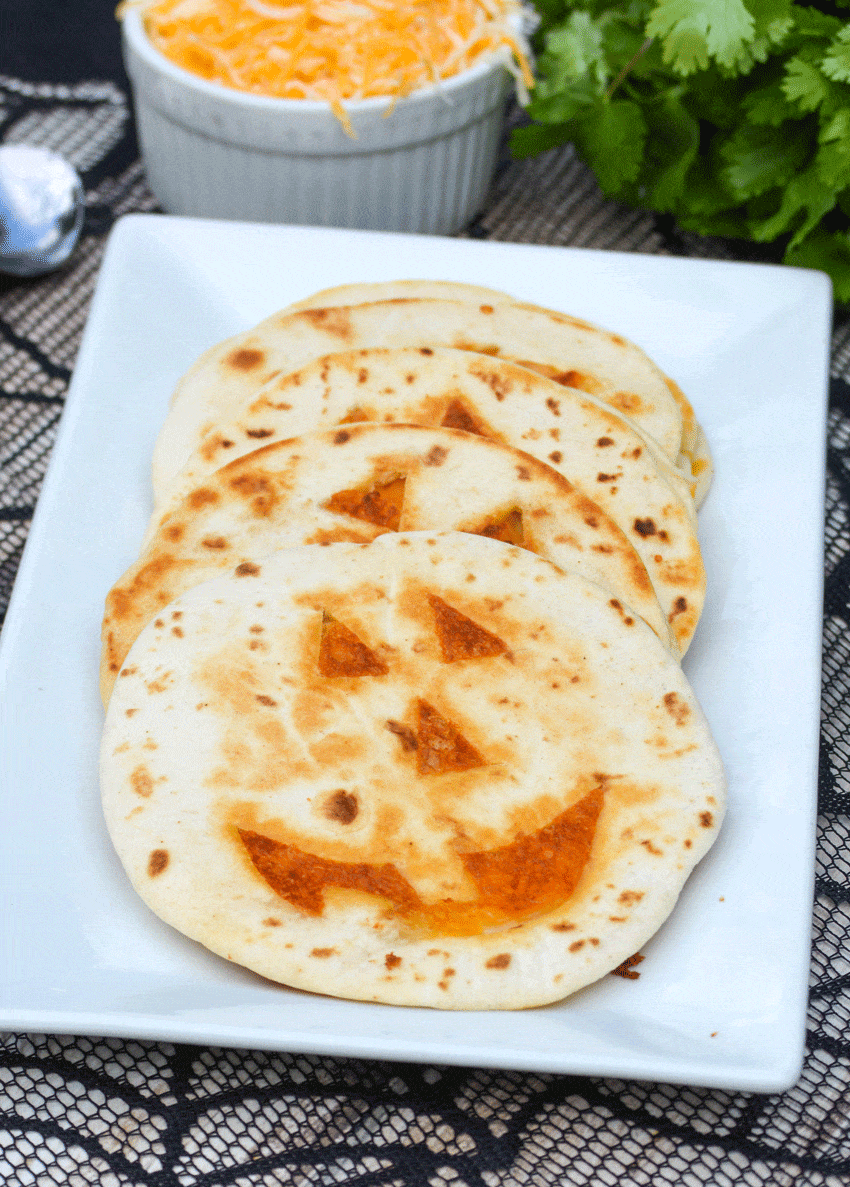 a row of pumpkin quesadillas arranged on a white serving platter