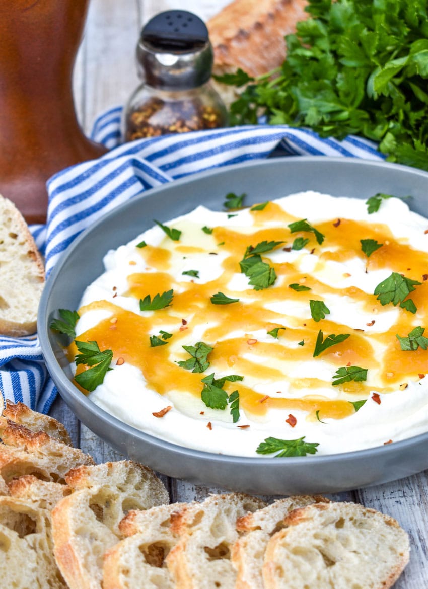 whipped ricotta dip in a shallow gray bowl topped with honey and fresh herbs