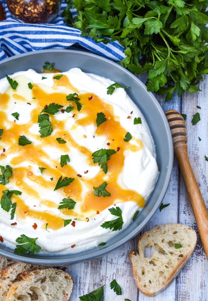 whipped ricotta cheese spread in a shallow gray bowl topped with honey and fresh herbs