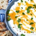 whipped ricotta cheese spread in a shallow gray bowl topped with honey and fresh herbs
