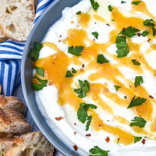 whipped ricotta cheese spread in a shallow gray bowl topped with honey and fresh herbs