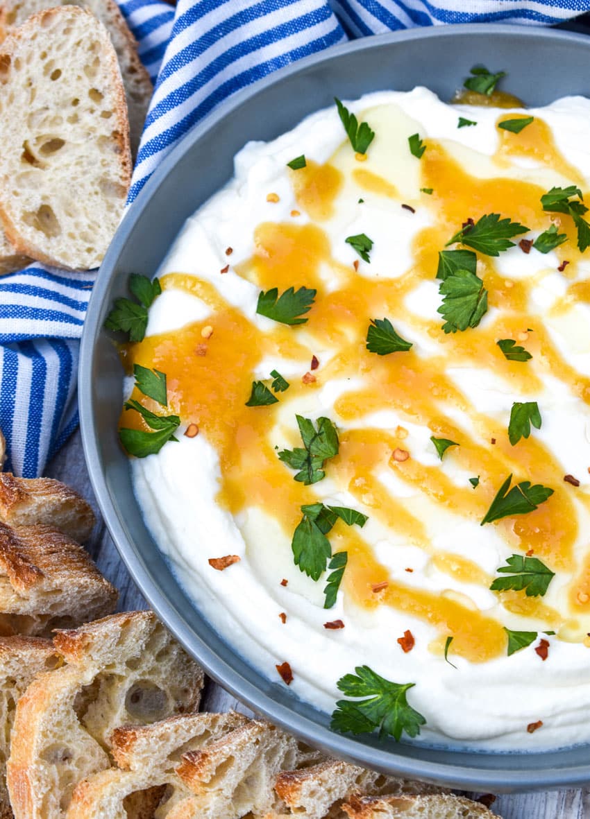 whipped ricotta cheese spread in a shallow gray bowl topped with honey and fresh herbs