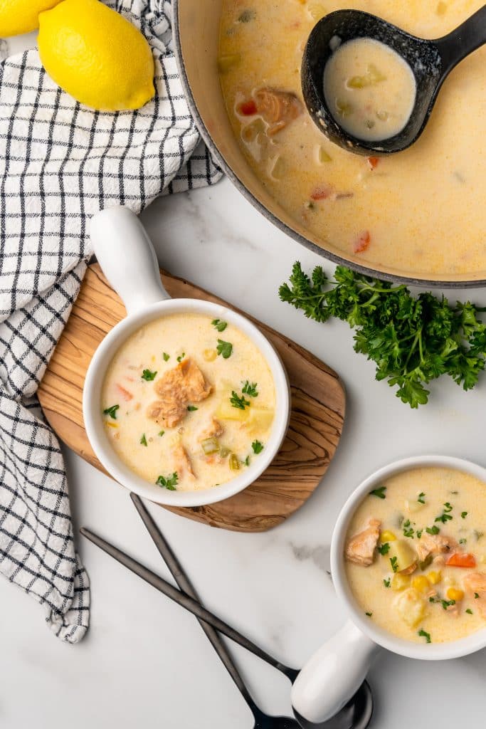 salmon chowder with canned salmon in white bowls next to a gray dutch oven