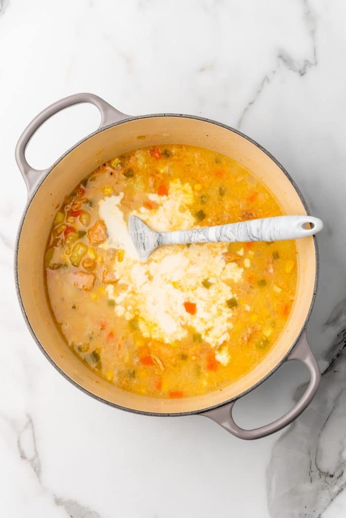 cream being added to a pot of salmon chowder with canned salmon