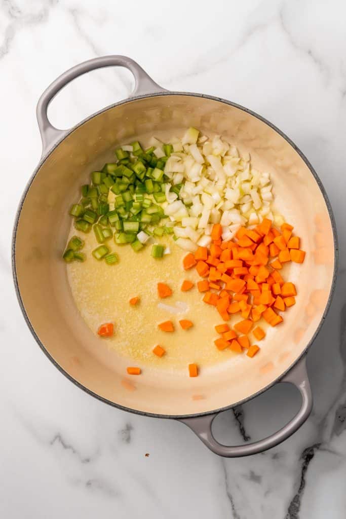 melted butter and diced vegetables in an enameled cast iron dutch oven