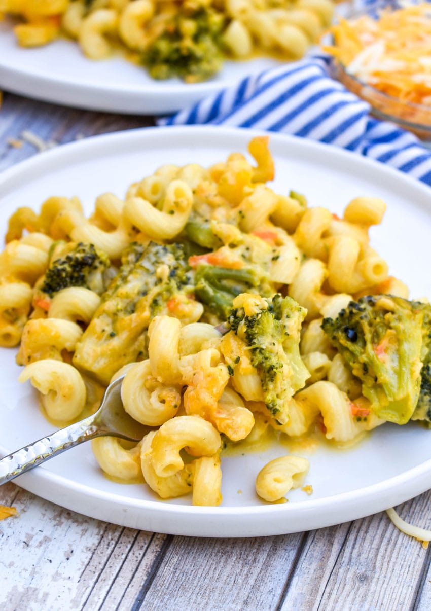 a silver fork resting on a plate of creamy broccoli cheddar mac and cheese