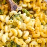 a wooden spoon in a casserole dish of creamy broccoli cheddar mac and cheese