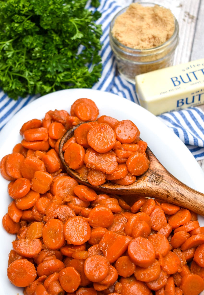 a wooden spoon resting in a bowl of brown sugar glazed canned carrots