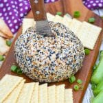 a wood handled spreader sticking out of the center of an everything bagel cheese ball