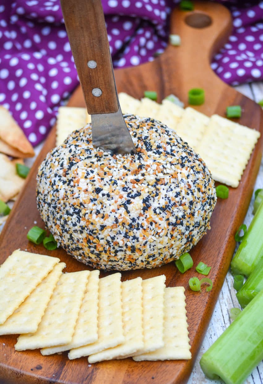 a wood handled spreader sticking out of the center of an everything bagel cheese ball