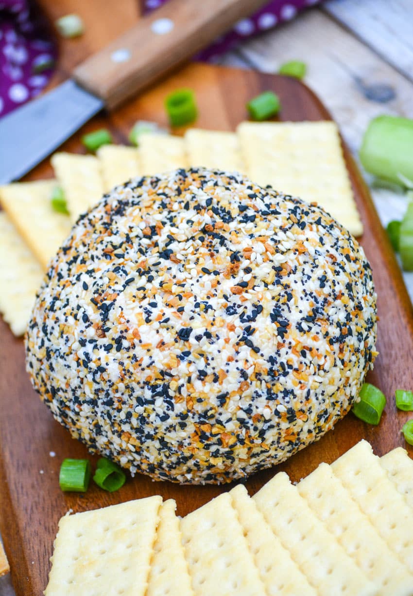 Everything Bagel Cheese Ball everything bagel cheese ball on a wooden cutting board surrounded by buttery crackers