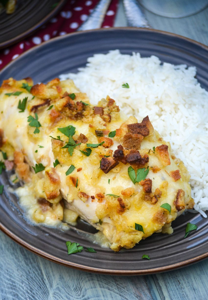 a piece of baked chicken in wine sauce on a brown dinner plate with steamed white rice on the side