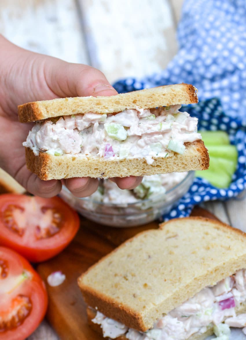 a hand holding up half a sandwich made with leftover turkey salad