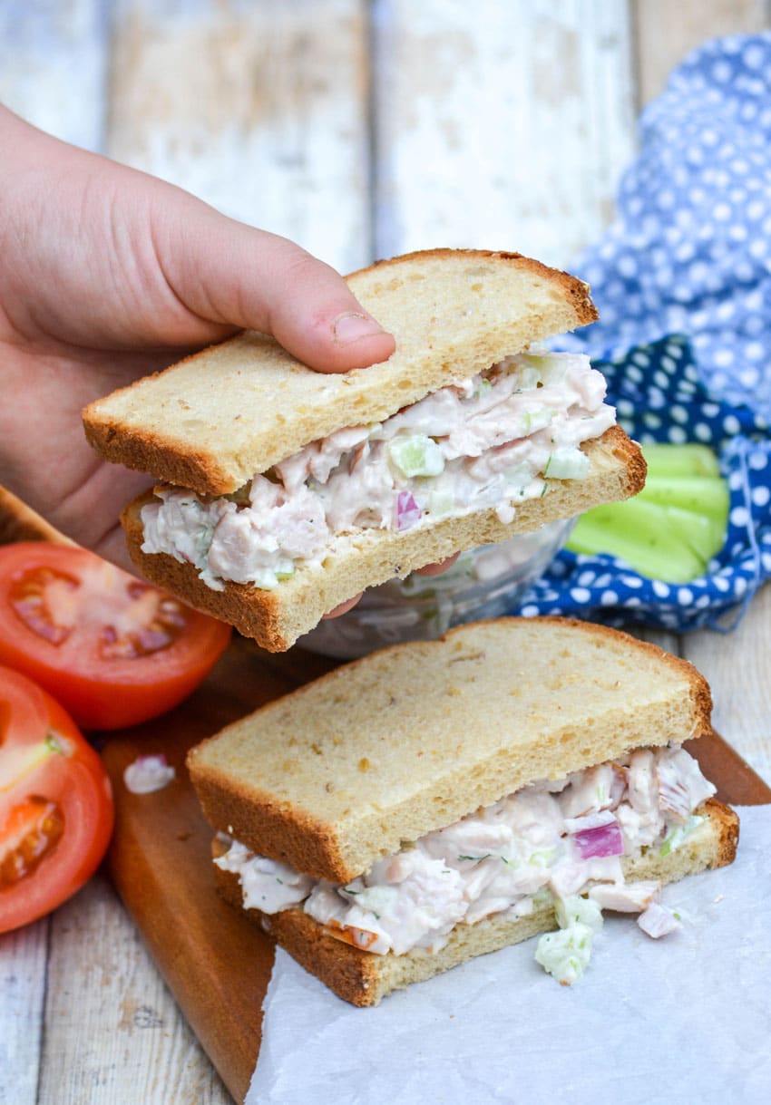 a hand holding up half a sandwich made with leftover turkey salad