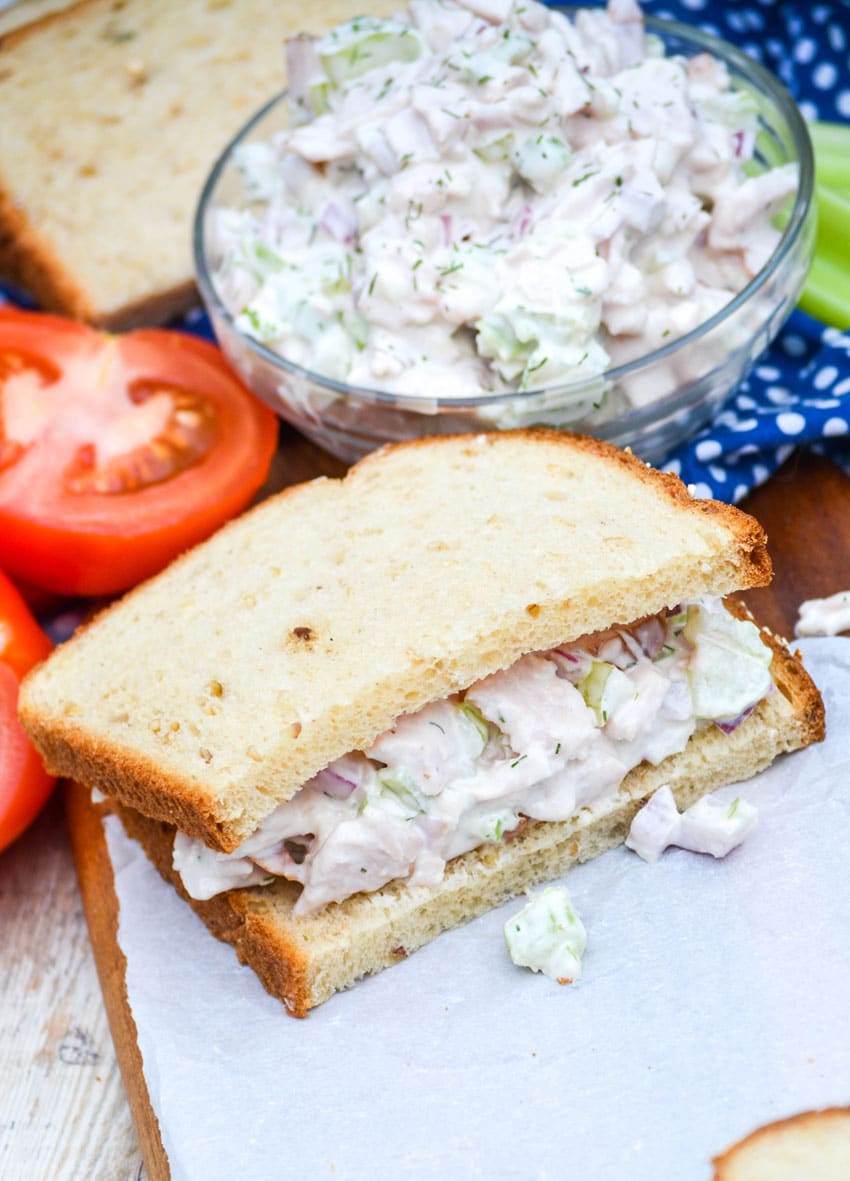 half of a leftover turkey sandwich on a white parchment paper covered wooden cutting board