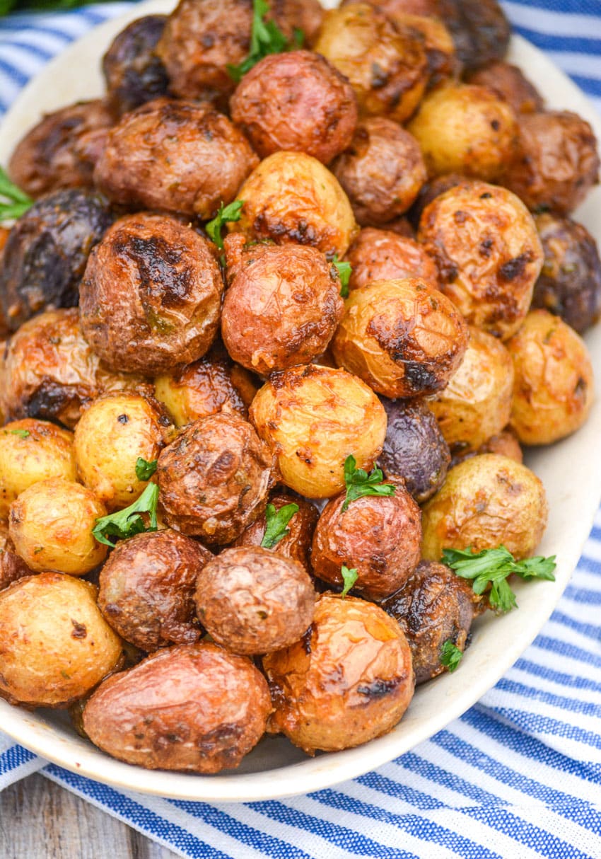 mayonnaise roasted potatoes topped with fresh parsley leaves on an oval serving platter