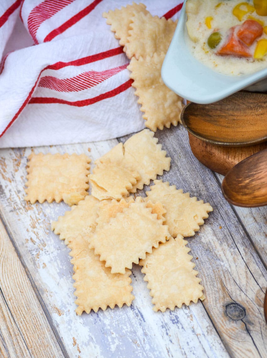 pie crust crackers on a wooden table next to a bowl of chicken soup