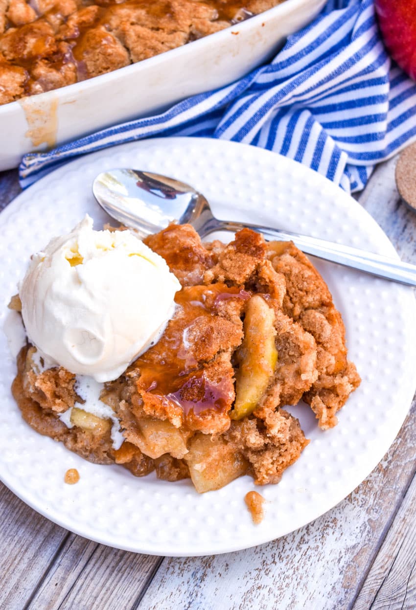 snickerdoodle apple cookie cobbler on a white plate with a large scoop of melting vanilla ice cream