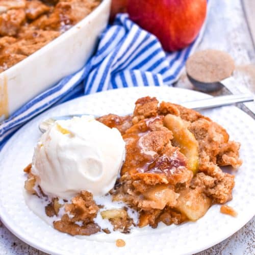 snickerdoodle apple cookie cobbler on a white plate with a large scoop of melting vanilla ice cream