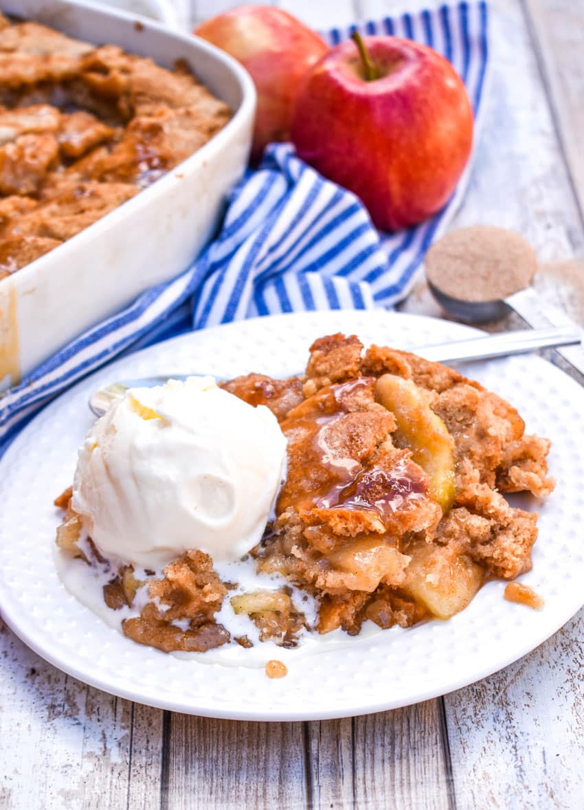 snickerdoodle apple cookie cobbler on a white plate with a large scoop of melting vanilla ice cream