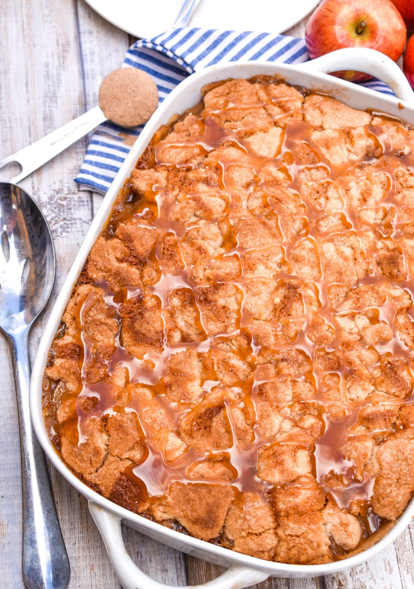 caramel sauce topped snickerdoodle apple cobbler in a white baking dish