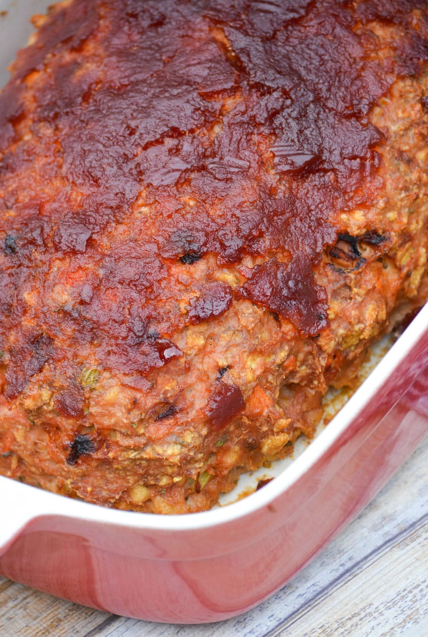 a baked, cranberry sauce topped turkey meatloaf in a red casserole dish