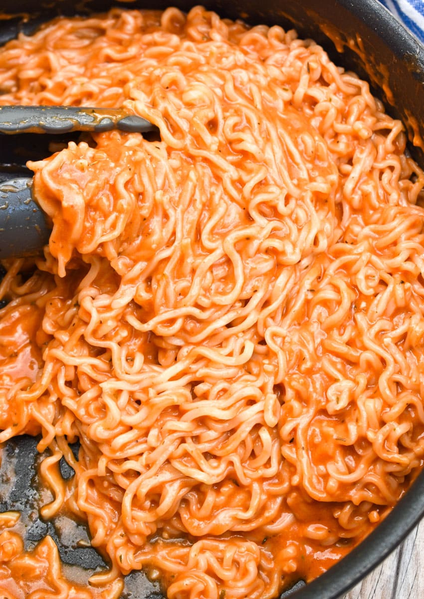 tomato soup ramen in a black skillet with tongs
