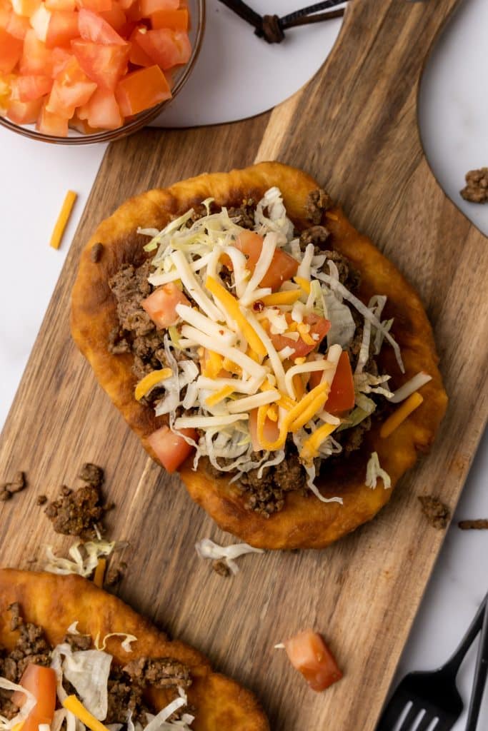 navajo tacos on indian fry bread on a wooden cutting board