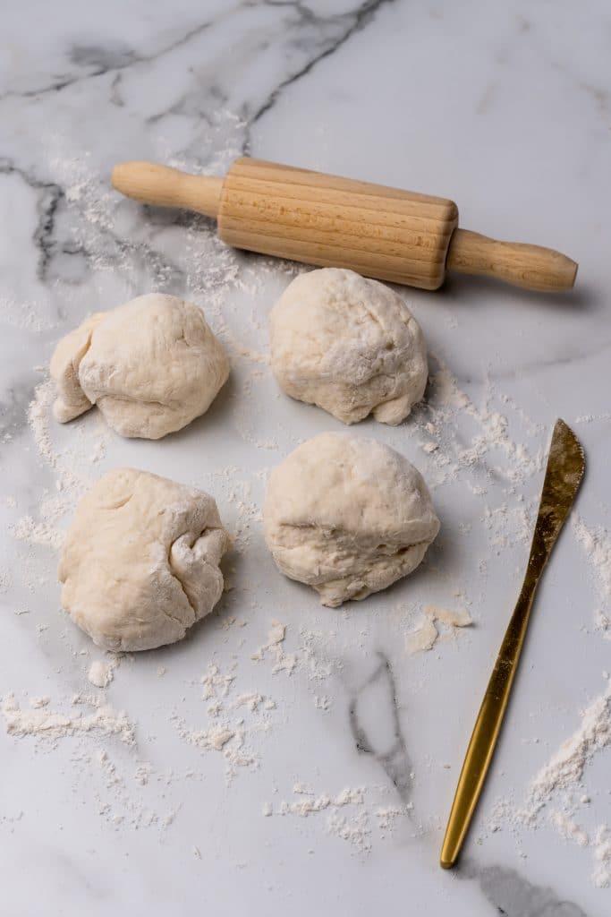 four balls of dough on a floured counter top