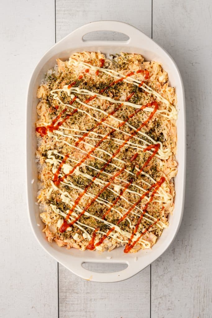 prepared sushi bake in a white casserole dish ready to go in the oven
