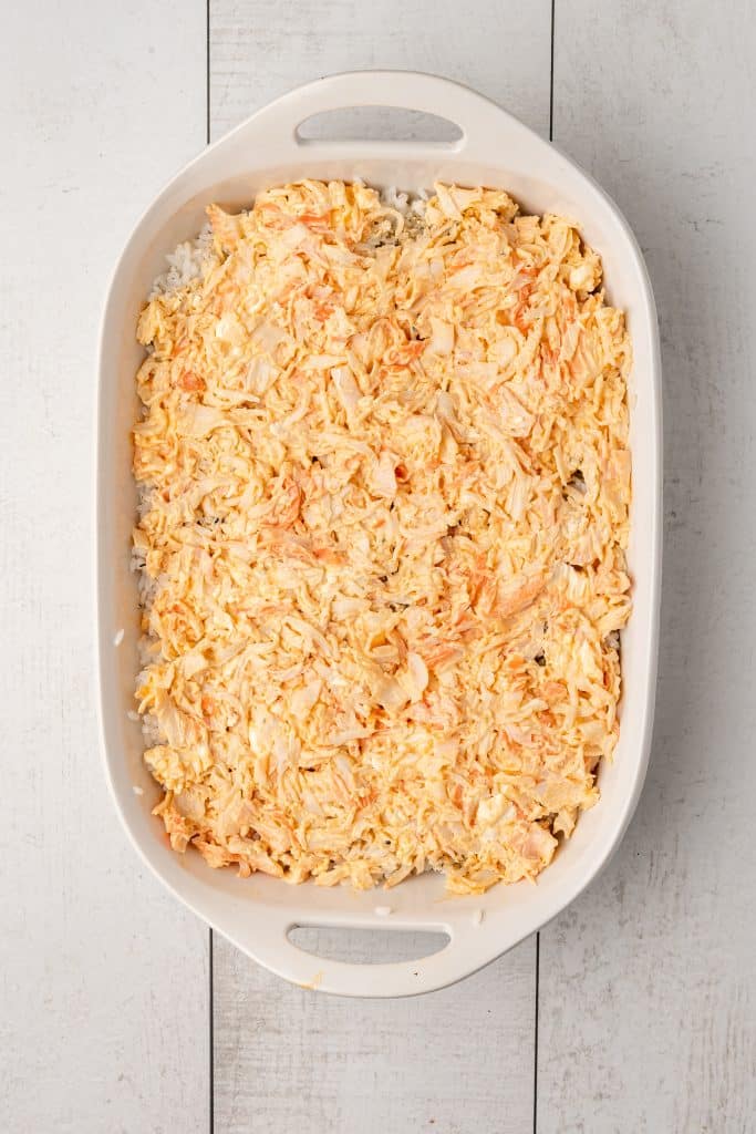 creamy crab mixture spread over seasoned rice in a white casserole dish