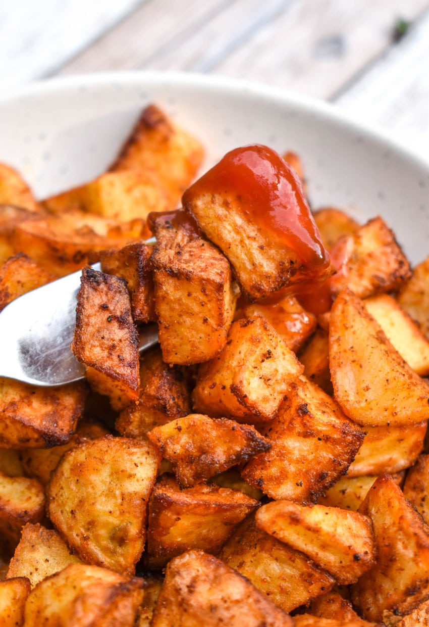 crispy air fryer breakfast potatoes in a shallow white bowl with a silver fork