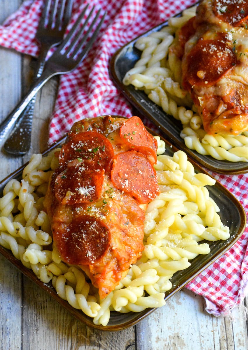 easy pizza chicken served over beds of cooked pasta on small brown plates