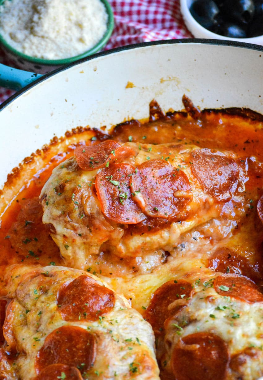 baked pepperoni pizza topped chicken breasts in a cast iron skillet