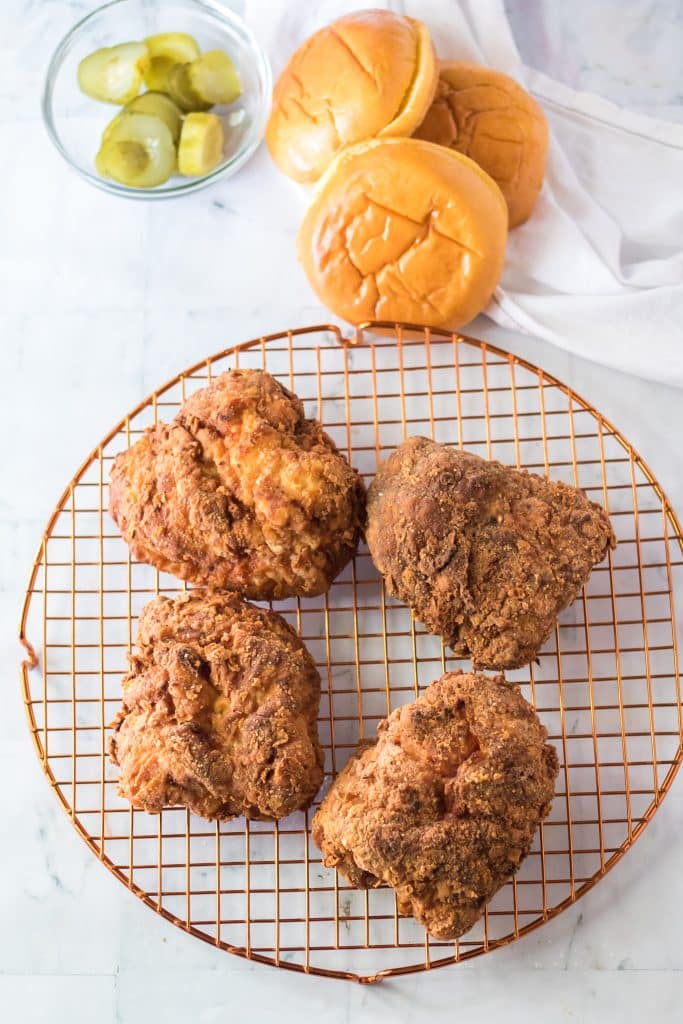 copycat popeyes fried chicken breasts on a metal cooling rack