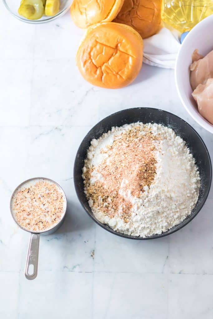 a bowl of seasoned flour and a measuring cup filled with seasoned milk