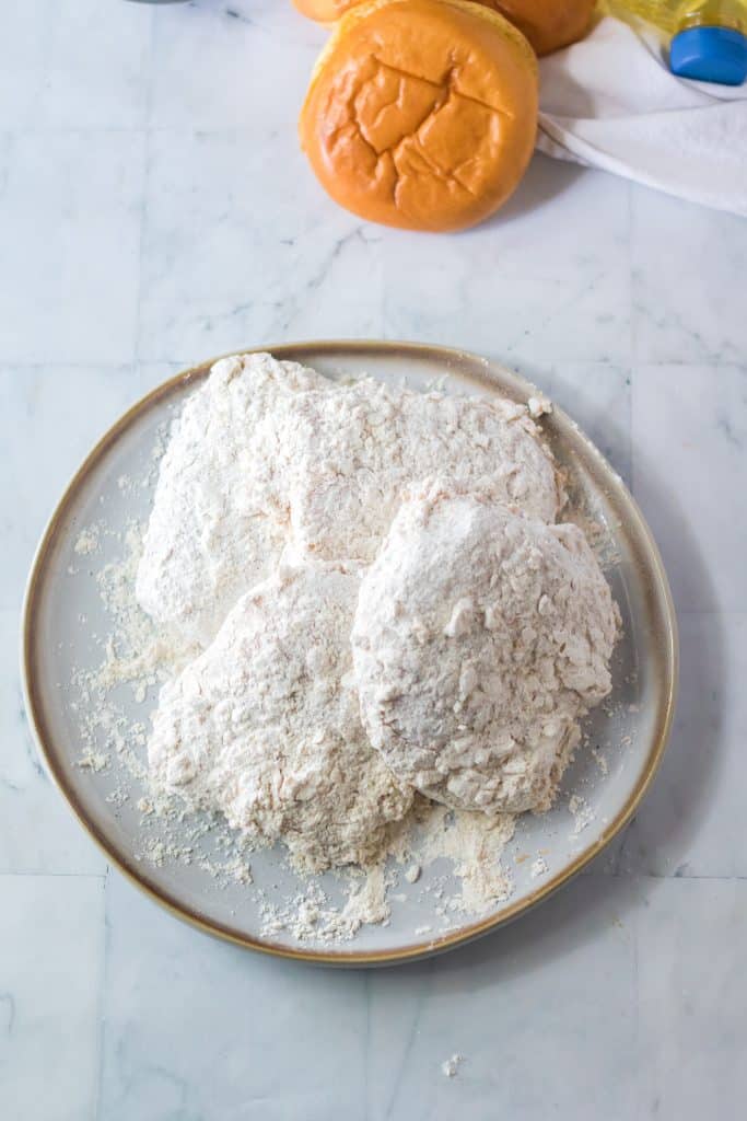 flour dredged chicken breasts on a white plate