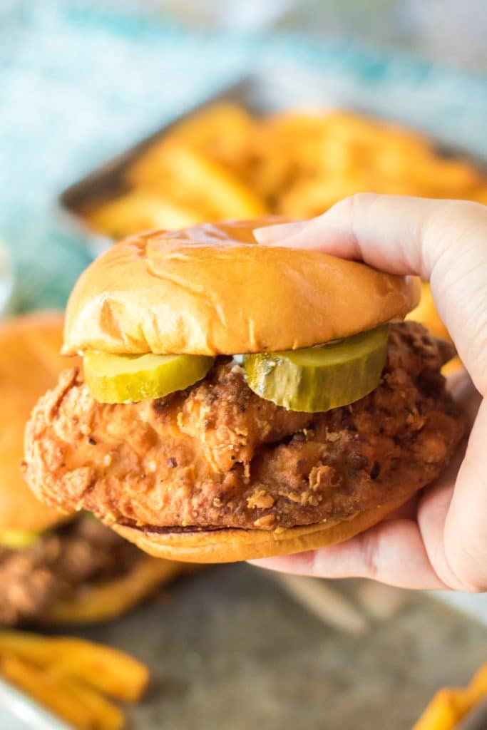 a hand holding a copycat popeyes chicken sandwich