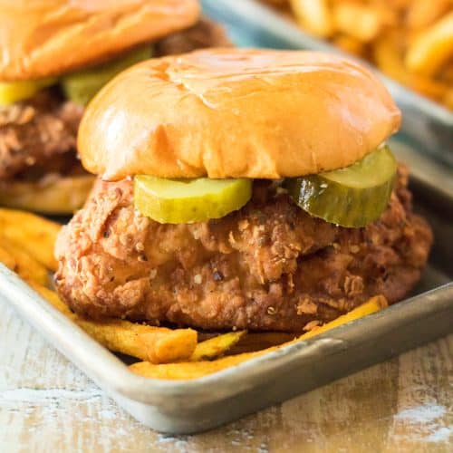 two copycat popeyes chicken sandwiches on a metal tray with fries