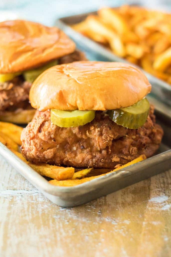 two copycat popeyes chicken sandwiches on a metal tray with fries