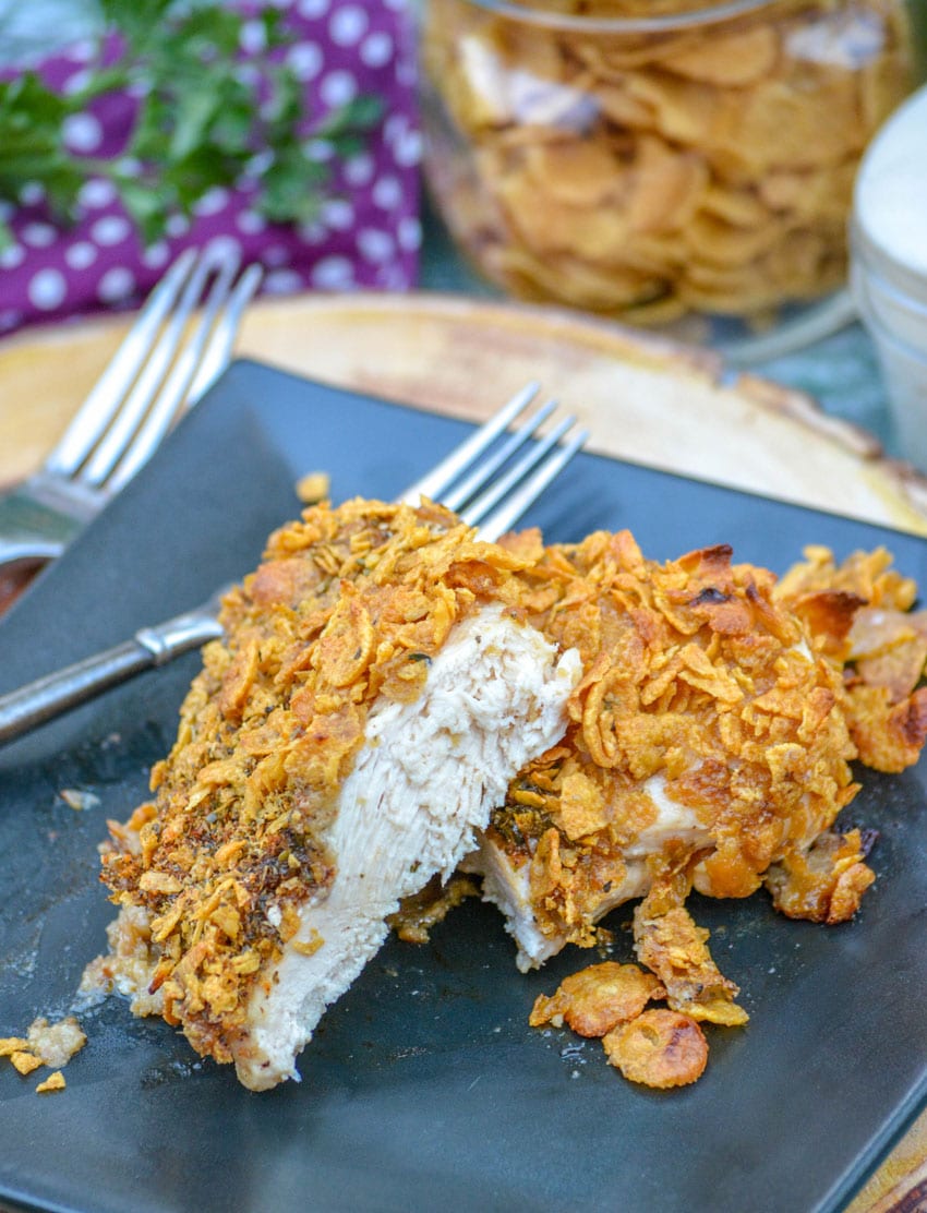 a sliced piece of baked crispy cornflake chicken on a black plate