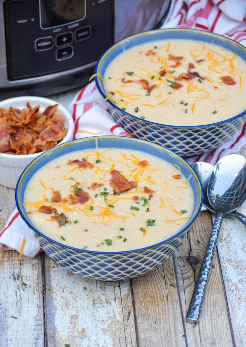 two bowls of slow cooker potato soup in front of a crockpot