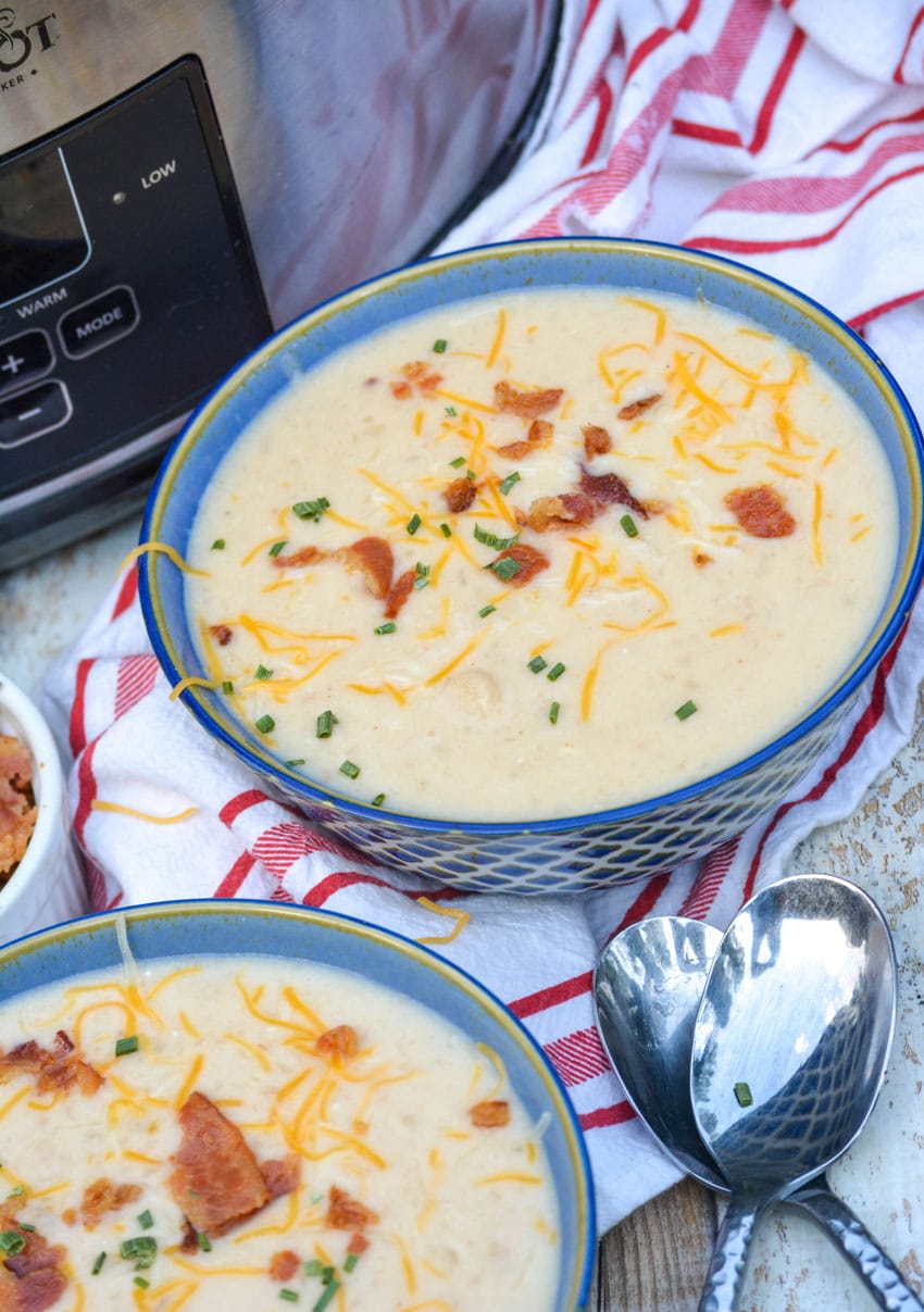 bowls of slow cooker potato soup in next to a crockpot