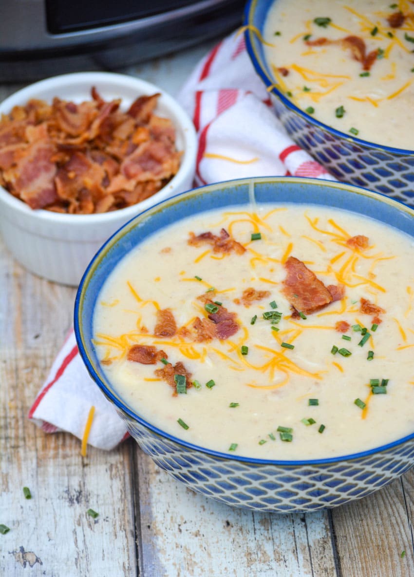 bowls of slow cooker potato soup in next to a crockpot