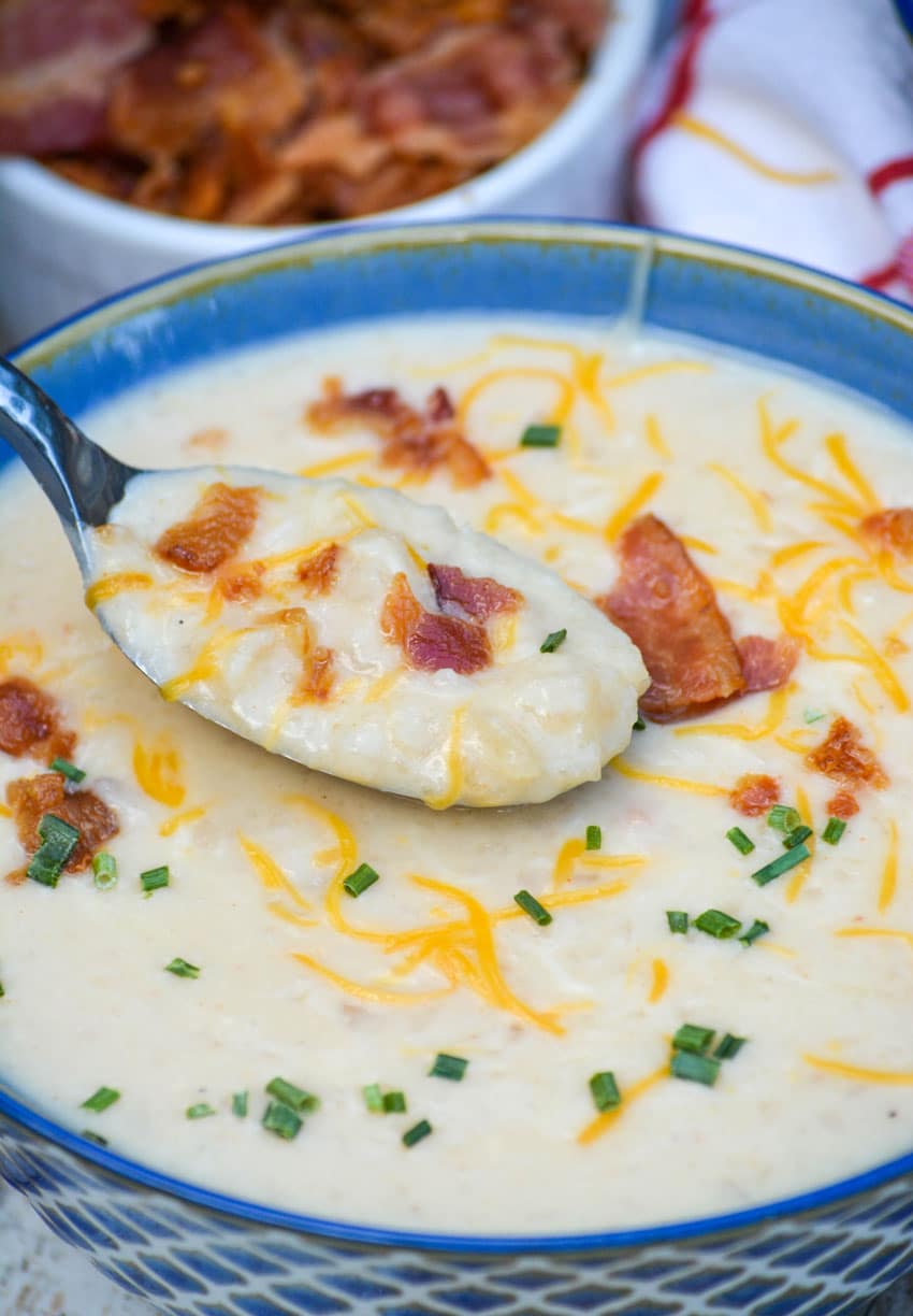 thick & creamy crockpot potato soup in a bowl topped with shredded cheese, crisp bacon, and chives