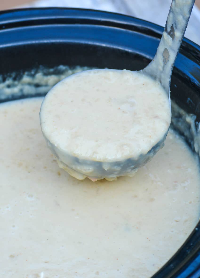 a silver ladle scooping creamy potato soup out of a black crockpot