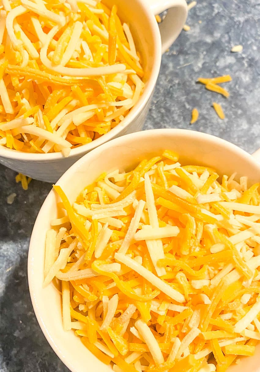 two mugs of pasta topped with shredded cheese
