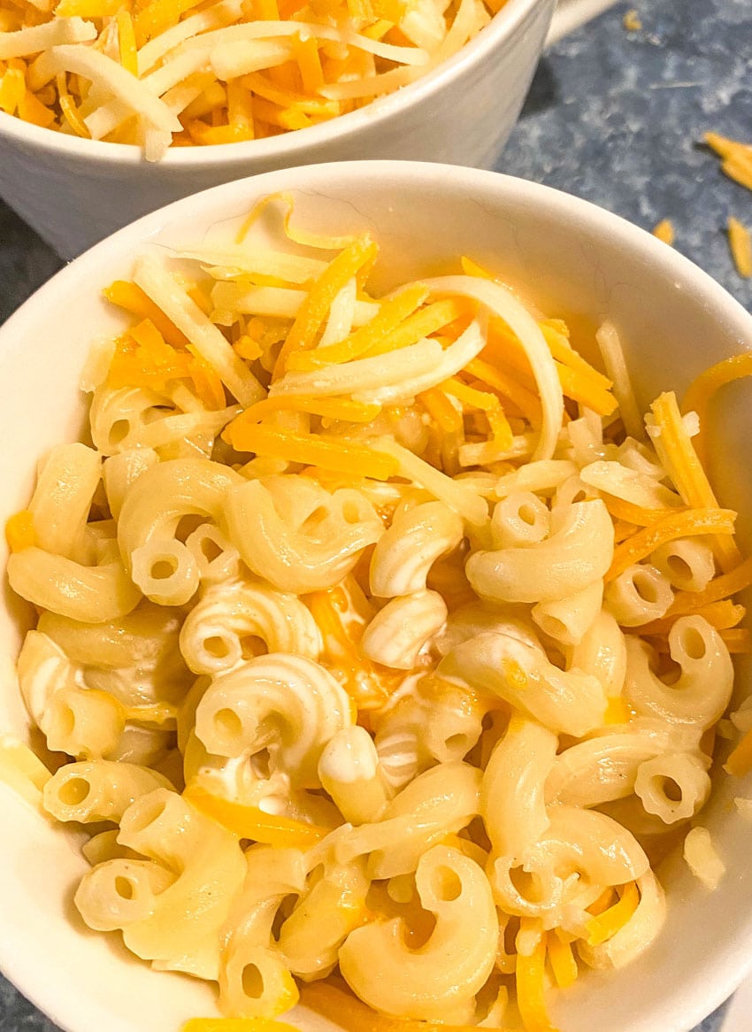 cheese butter & cream being stirred into hot pasta in a white mug